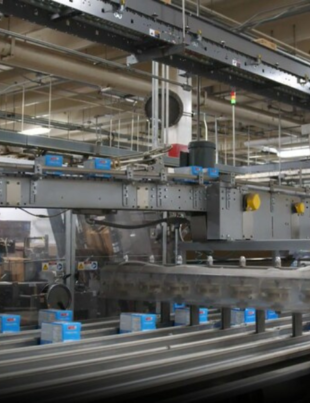 Image-of-the-interior-of-a-Kellanova-manufacturing-facility-with-several-blue-boxes-of-product-running-down-automated-grey-production-lines